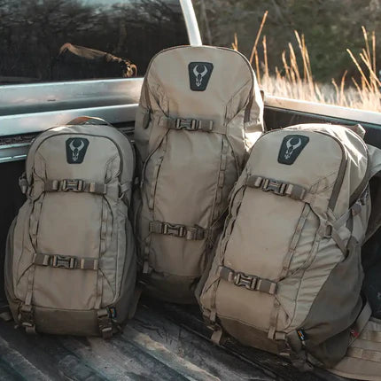 Three tan Moonrivers backpacks with skull logos sit in a truck bed, ready for outdoor adventure.