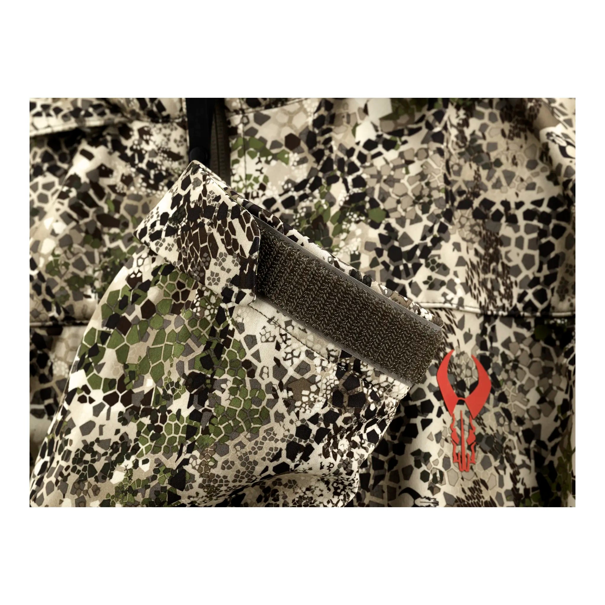 Close-up of camo fabric with a Velcro strap and a red Moonrivers skull logo on the lower right side.