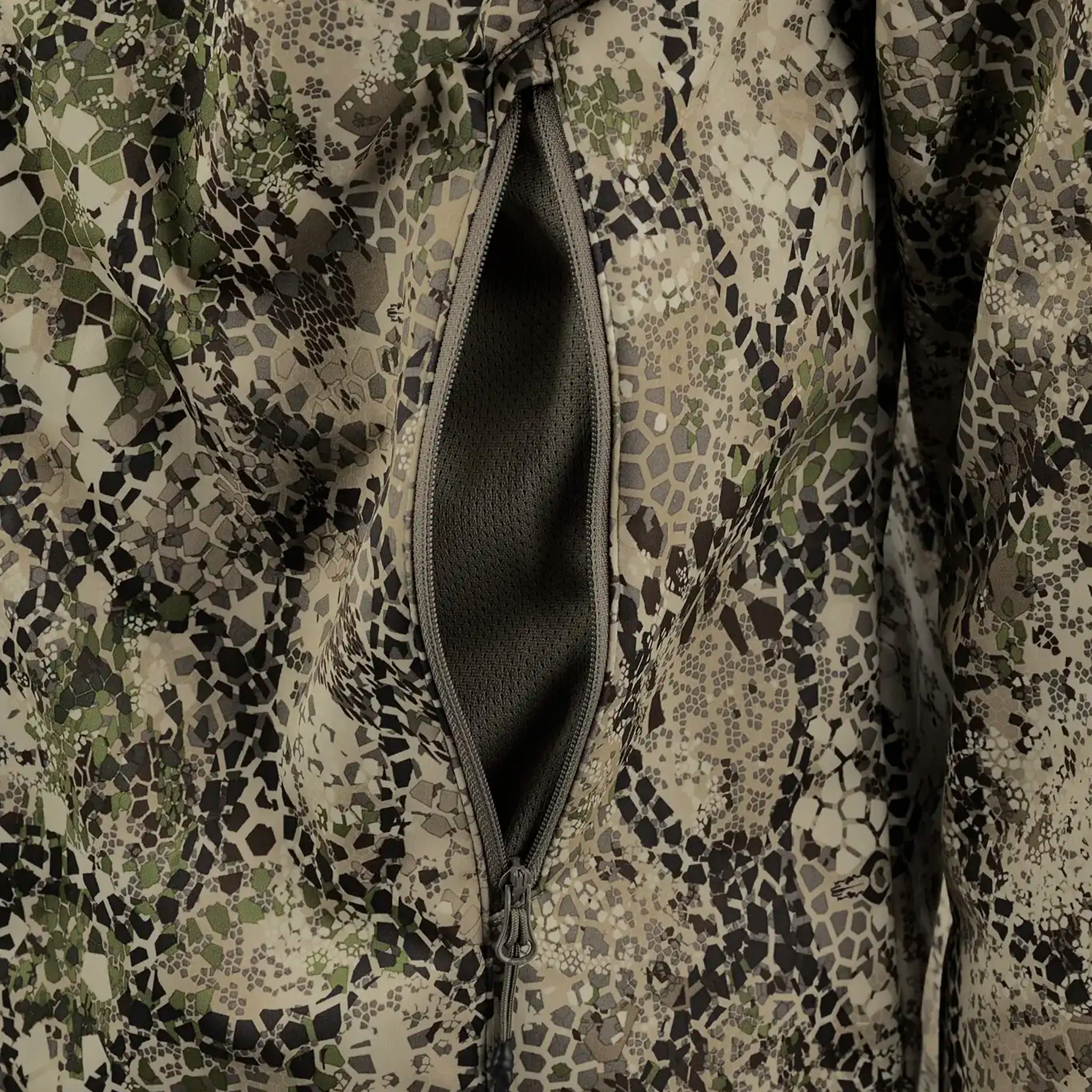 Close-up of a zippered pocket on camouflage fabric, showing mesh lining inside.