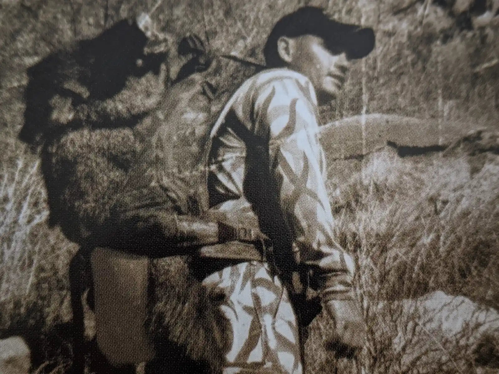 Hunter in camo carries a large animal on their back with a Moonrivers skull logo visible, outdoors in rugged terrain.