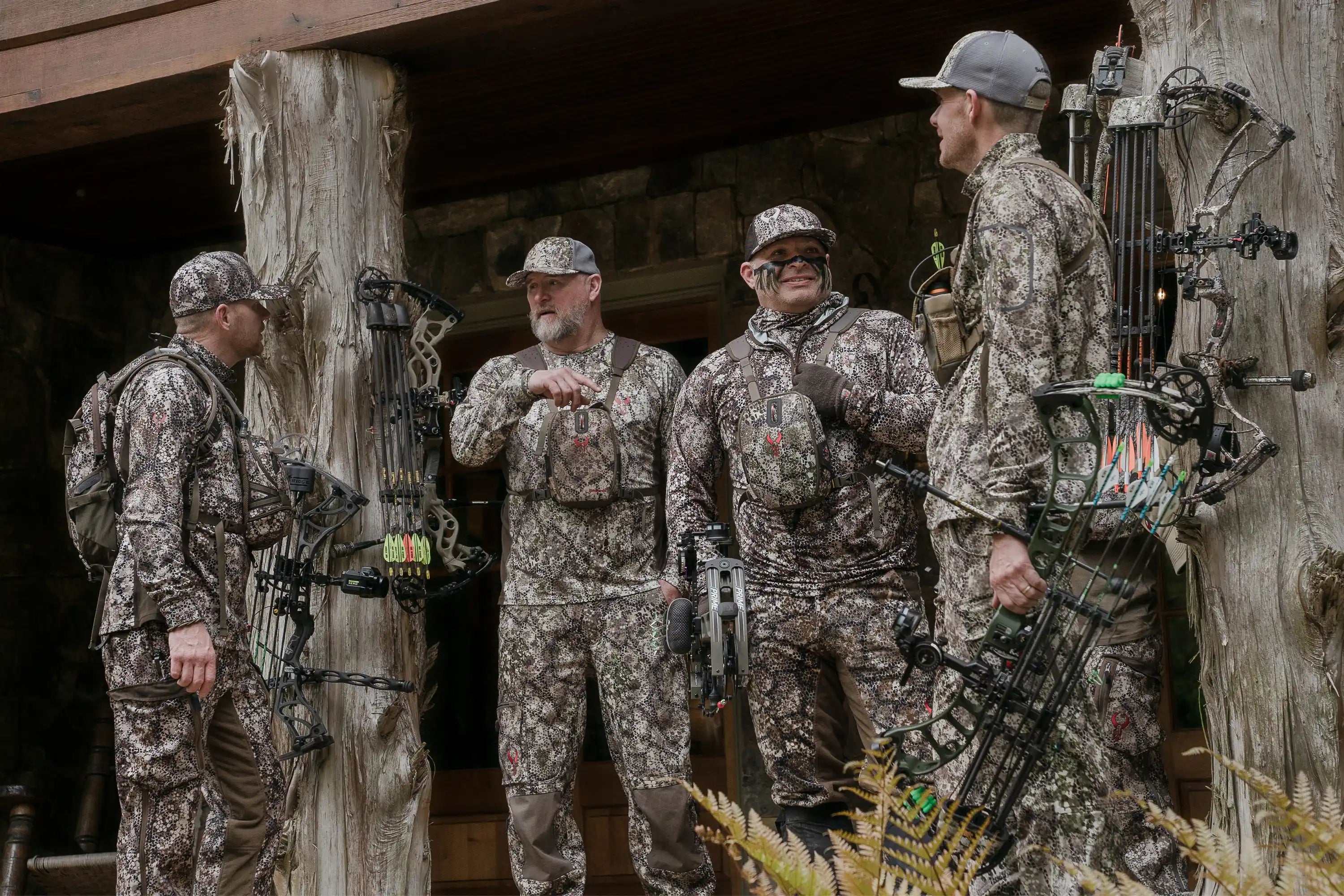 Four hunters in Moonrivers camo gear with bows, standing outdoors. Moonrivers skull logo visible on chest packs.
