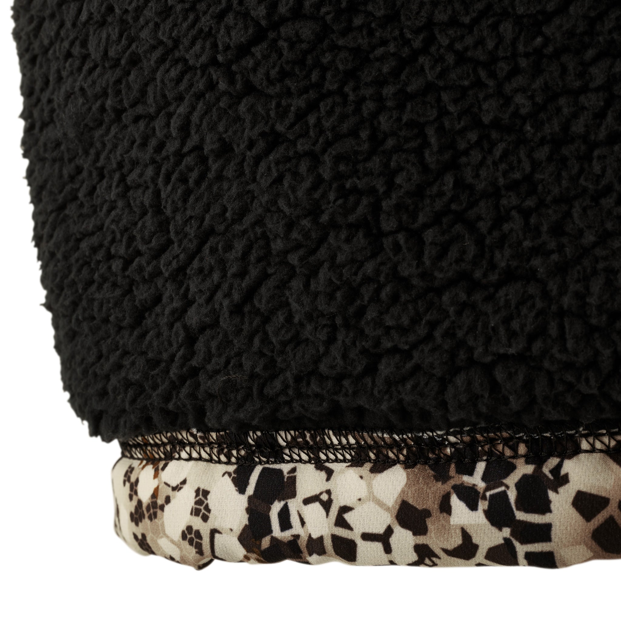 Close-up of Moonrivers fleece fabric with black sherpa texture and camo trim, featuring the signature skull logo pattern.