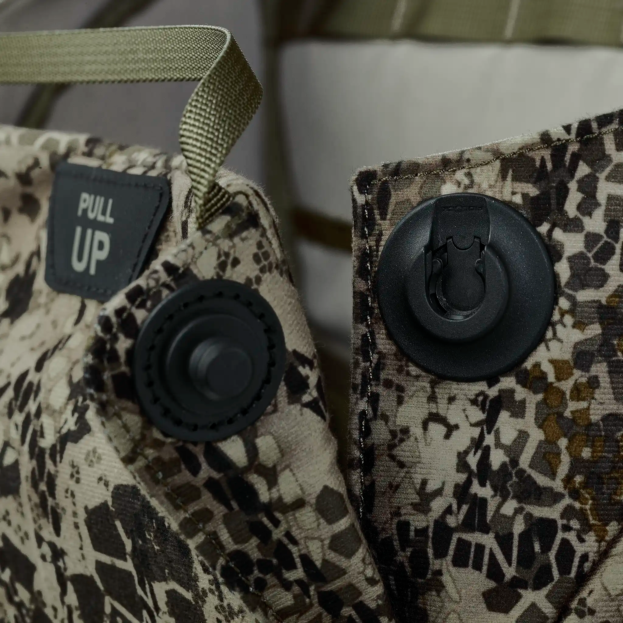 Close-up of camo fabric with Moonrivers Logo, hydration hose ports, and a "PULL UP" label for easy access.