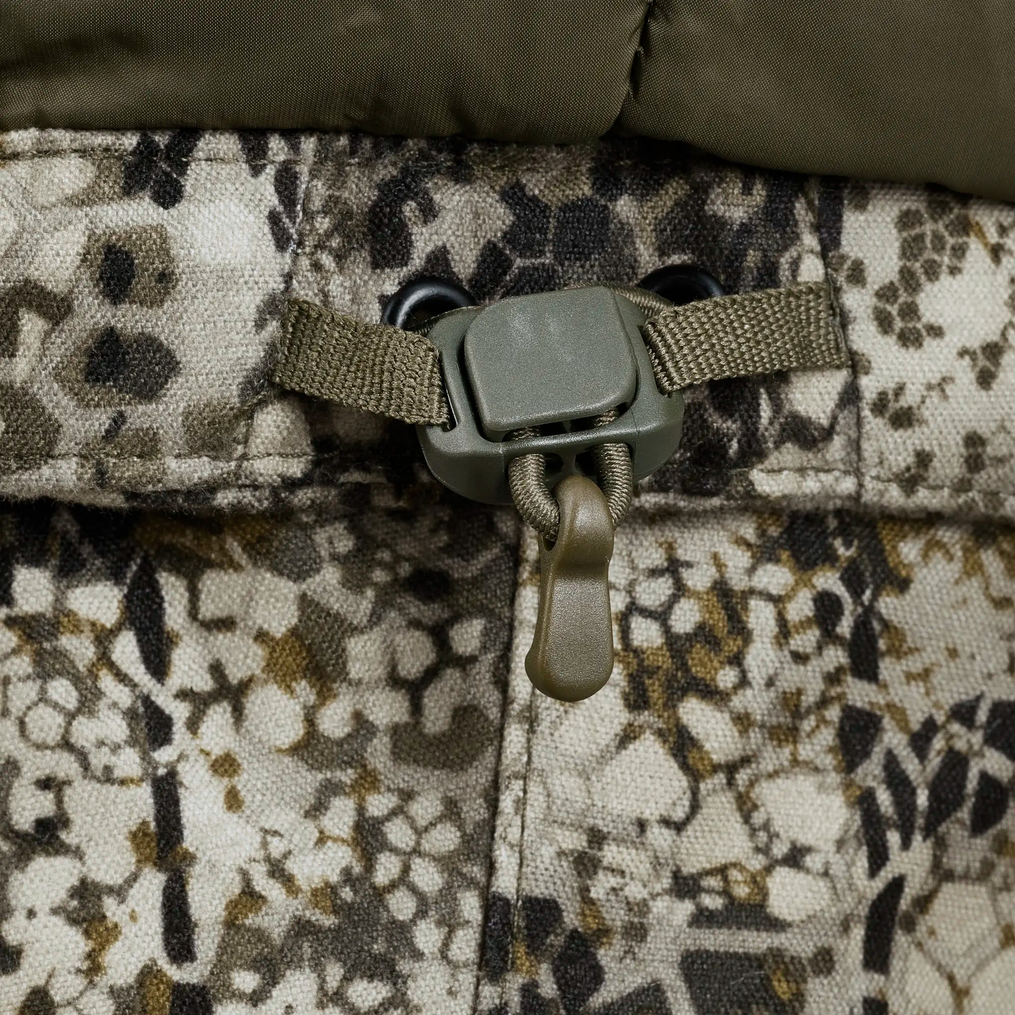 Close-up of Moonrivers camo fabric with a drawstring and skull logo cord lock for adjustable fit.