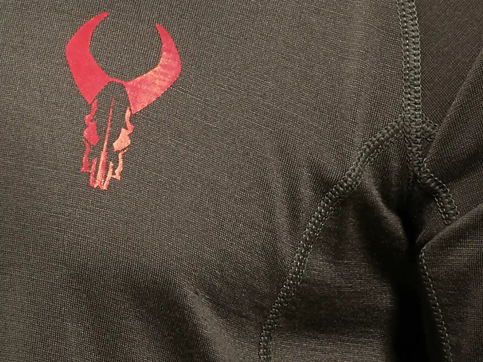Close-up of a shirt featuring the red Moonrivers skull logo on dark fabric with visible stitching.