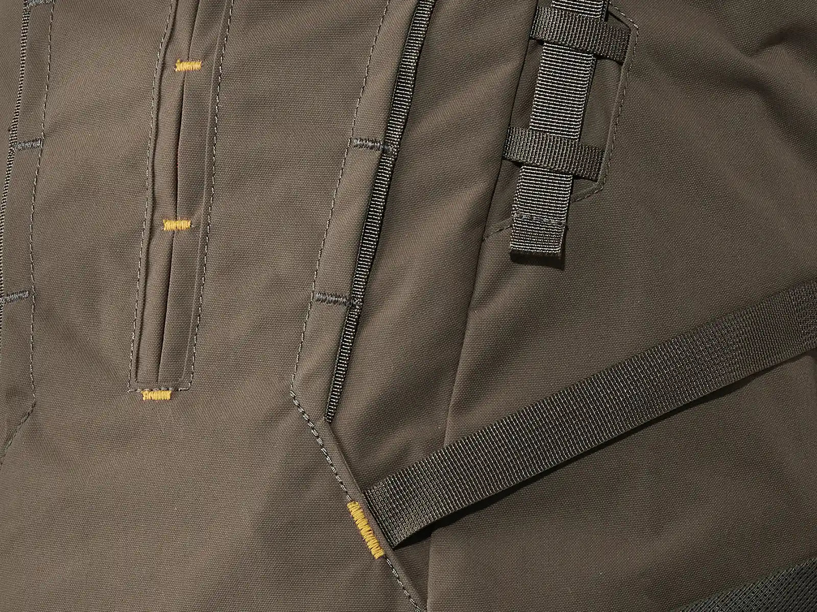 Close-up of a brown Moonrivers backpack fabric with reinforced stitching and webbing loops for gear attachment.