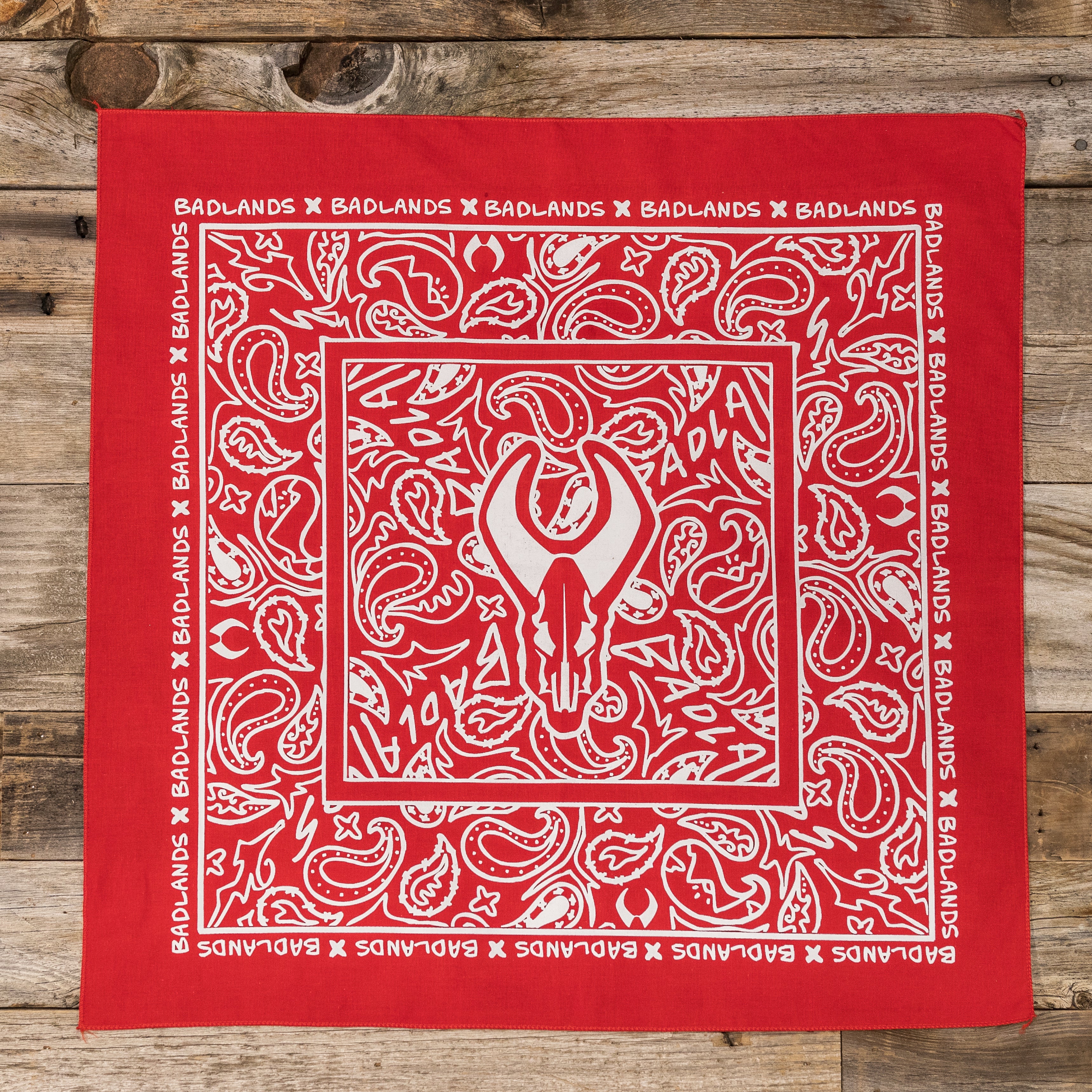 Red bandana with white paisley pattern, Moonrivers Logo (skull) in center, and "BADLANDS" text along the border.