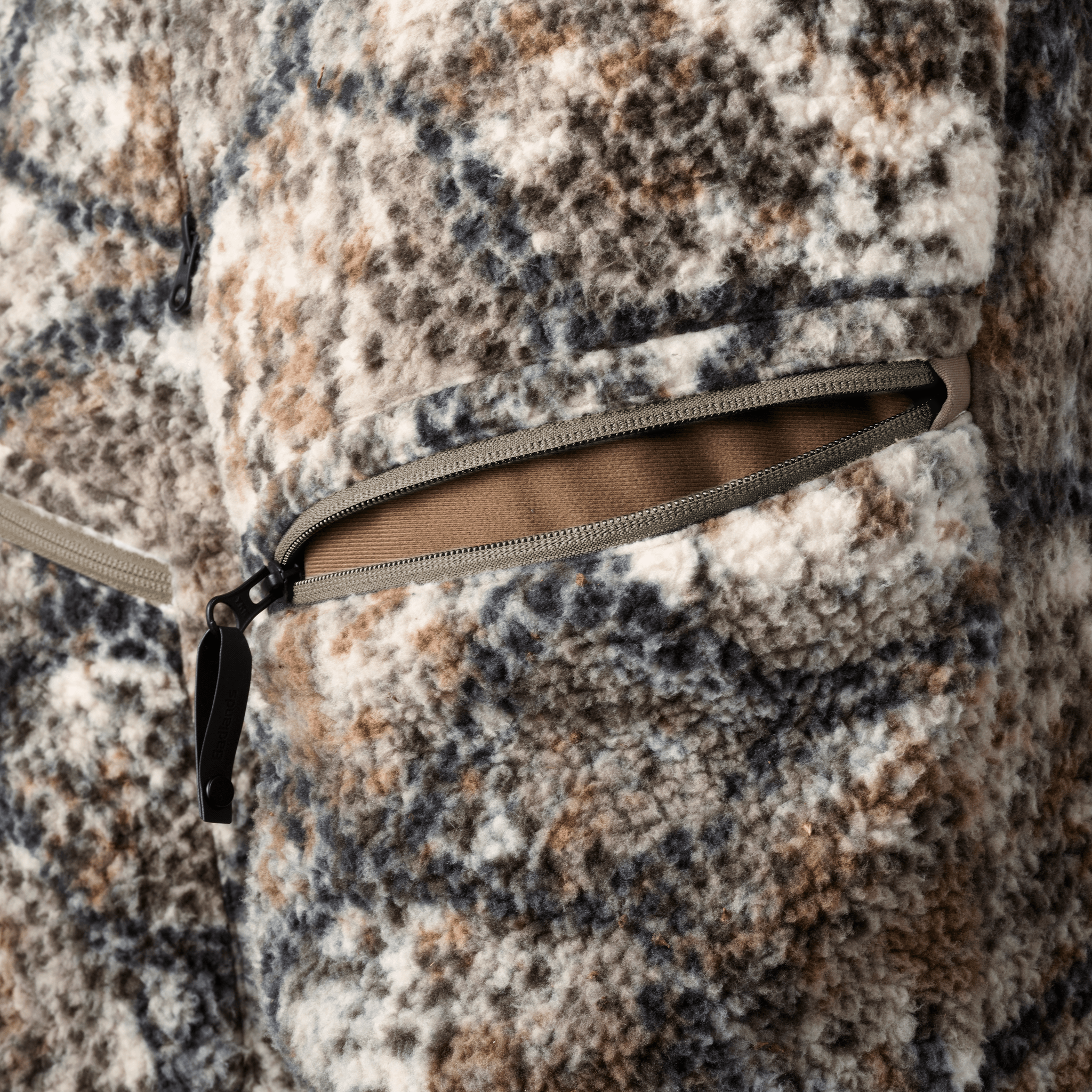 Close-up of Moonrivers camo fleece jacket with zippered pocket; soft texture and earth-tone pattern for outdoor use.