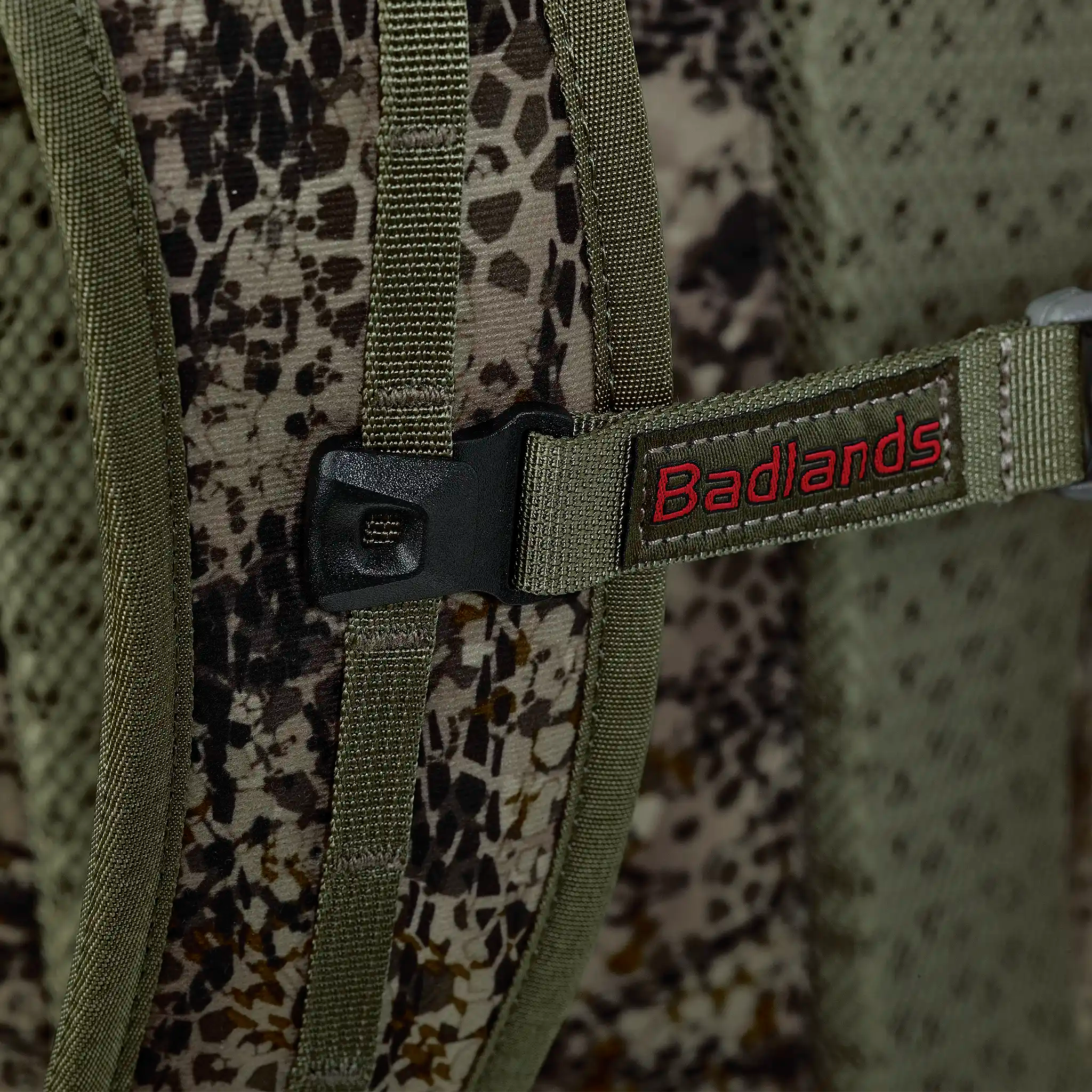 Close-up of a camouflage backpack strap with a black buckle and red Moonrivers logo, designed for outdoor use.