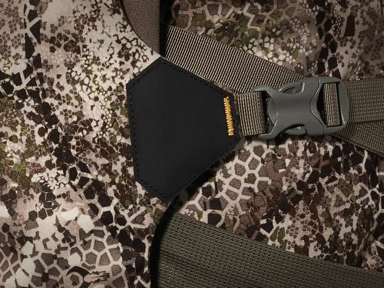 Close-up of Moonrivers camo fabric, buckle, and logo skull patch; textured pattern aids concealment for outdoor use.