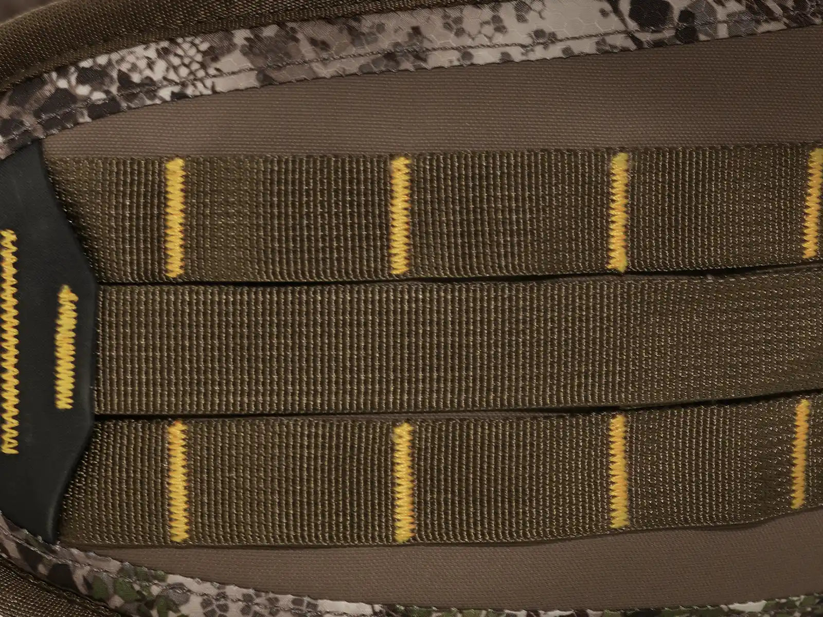 Close-up of Moonrivers camo fabric with reinforced yellow stitching and webbing, featuring the Moonrivers skull logo.