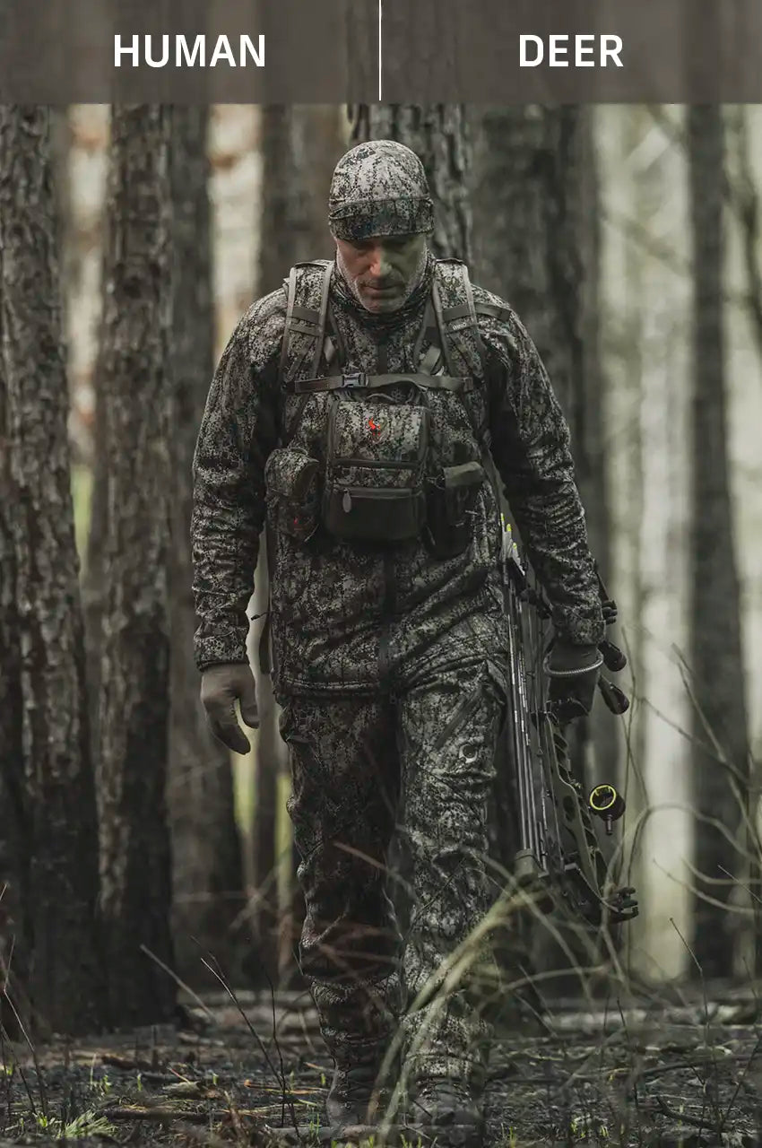 Hunter in Moonrivers camo with bow, Moonrivers skull logo visible, blending into forest for optimal concealment.