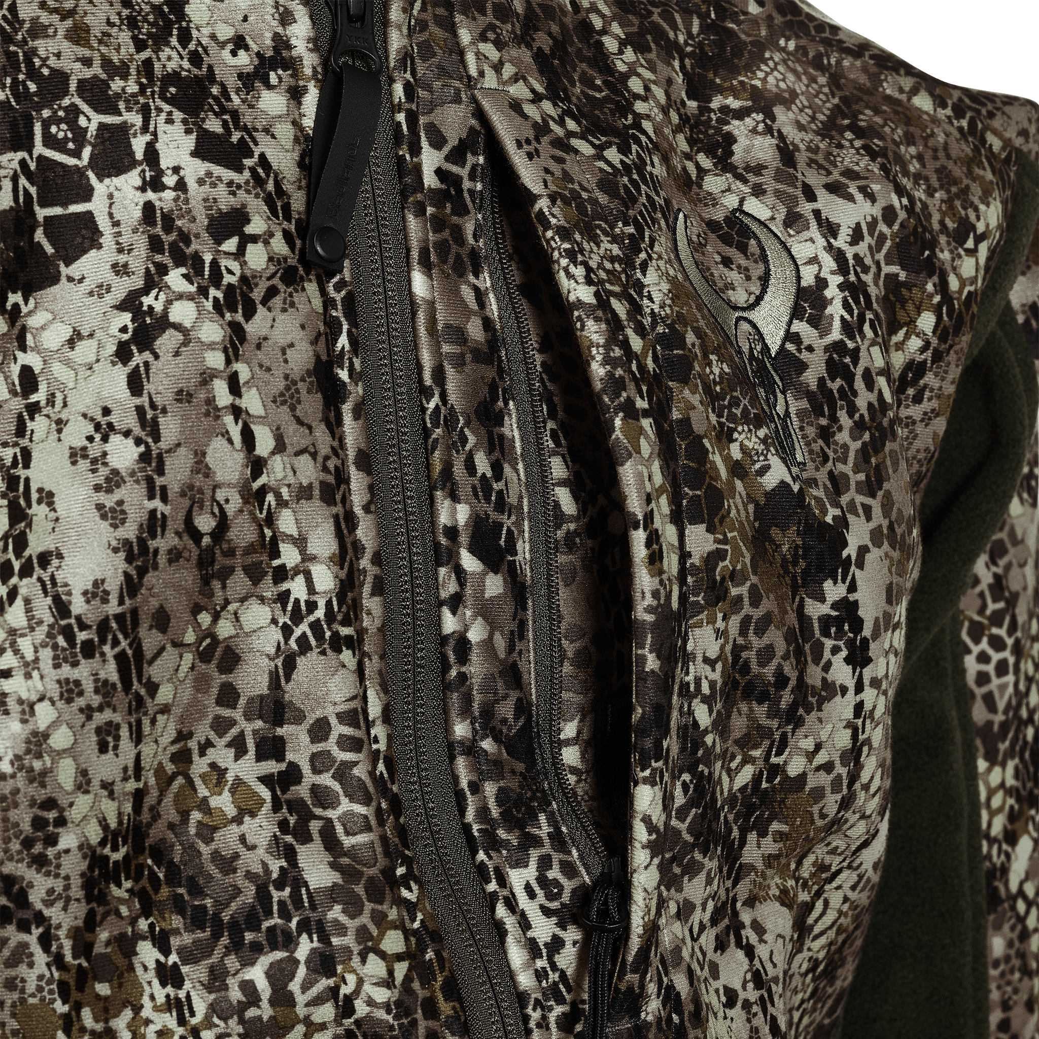 Close-up of a camo jacket with zippers and the Moonrivers skull logo on the chest, designed for outdoor use.