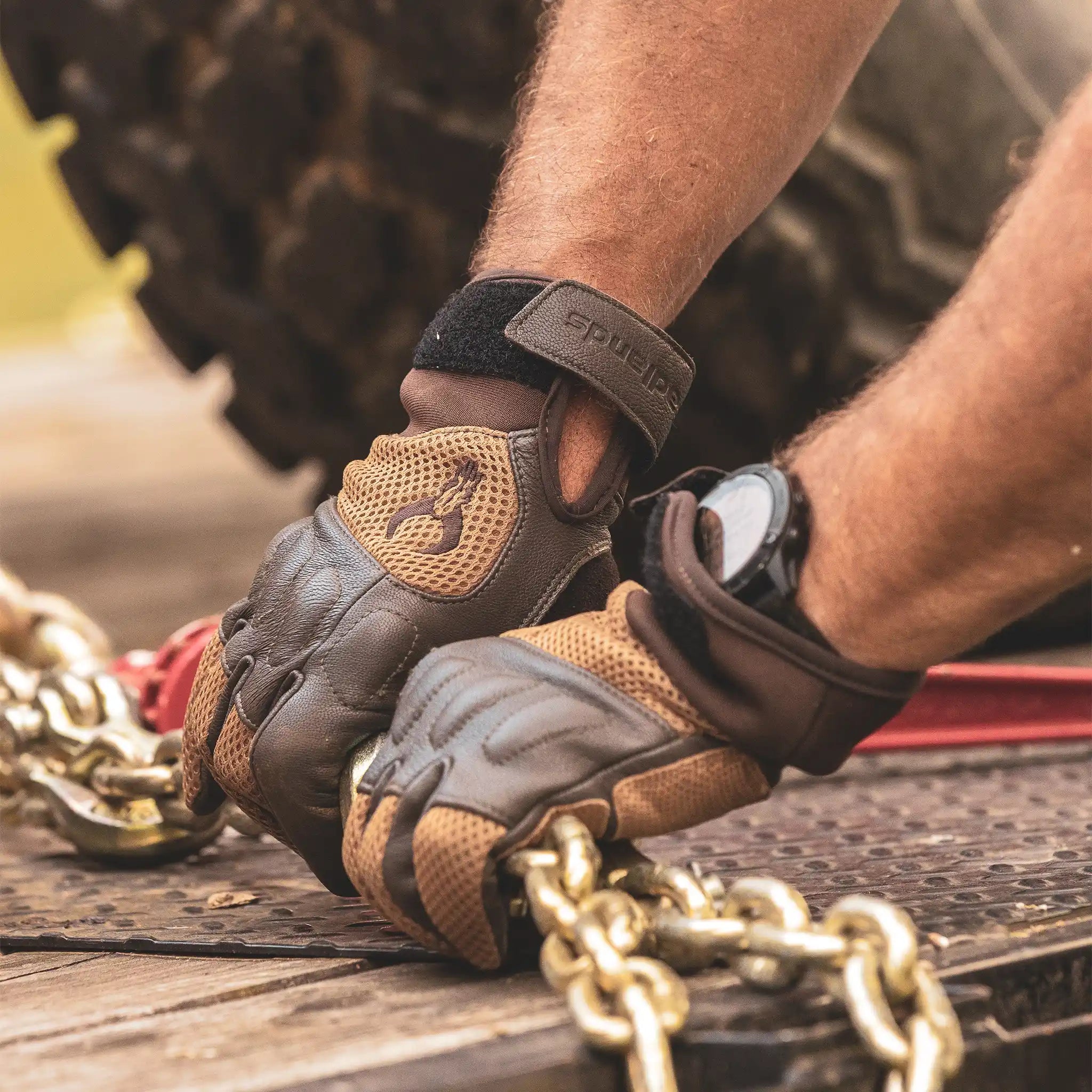 Gloved hands with Moonrivers Logo securing heavy chains on a flatbed trailer; watch visible on wrist.
